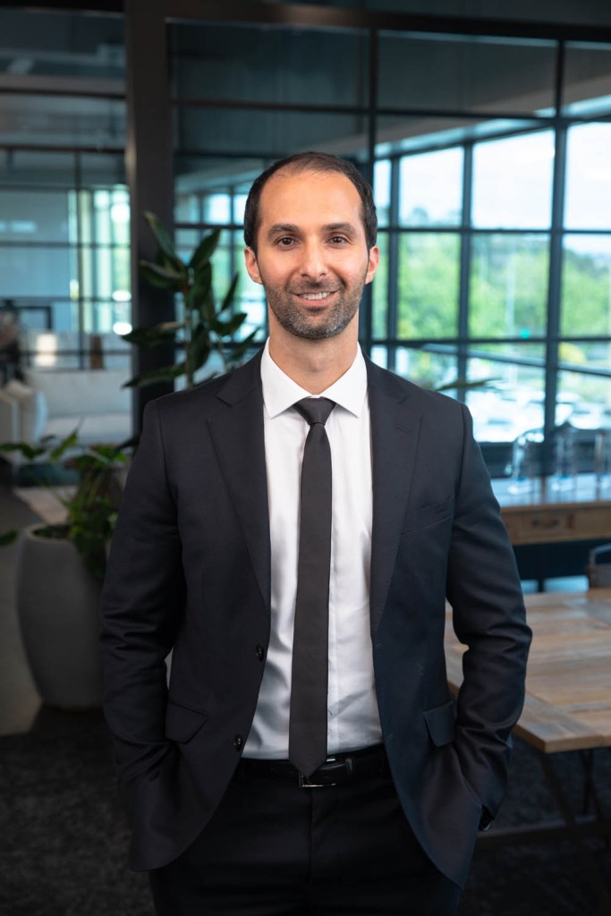 Polished professional real estate agent in Rothesay Bay posed in a well-lit office setting.