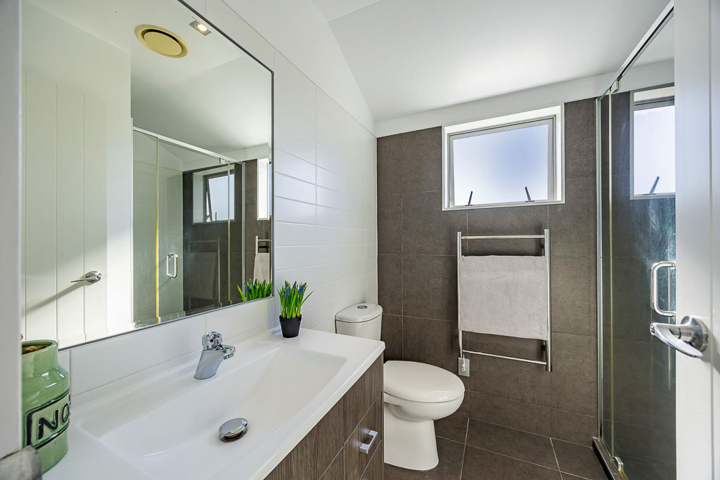 Full-size family bathroom in Albany Heights townhouse featuring bathtub, shower, and tiled walls – ideal for growing families.