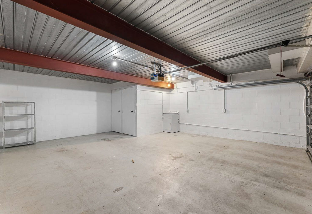 Secure double garage in affordable Albany home featuring exposed beams, concrete flooring, and built-in shelving – perfect for families or investors.