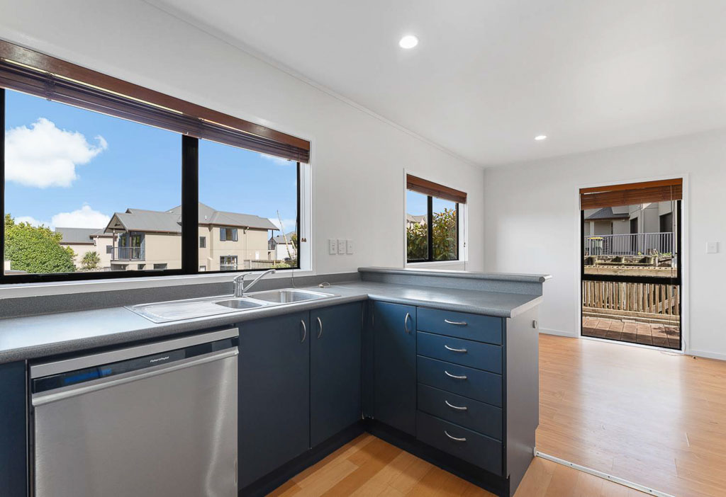 Open-plan kitchen in affordable Albany home featuring built-in dishwasher, breakfast bar, and flow to living area – ideal for young families.