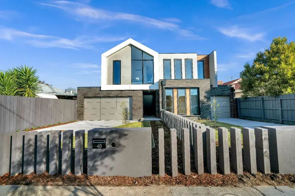 Contemporary two-story home with modern architecture, black brick exterior, and large front windows on a sunny day.