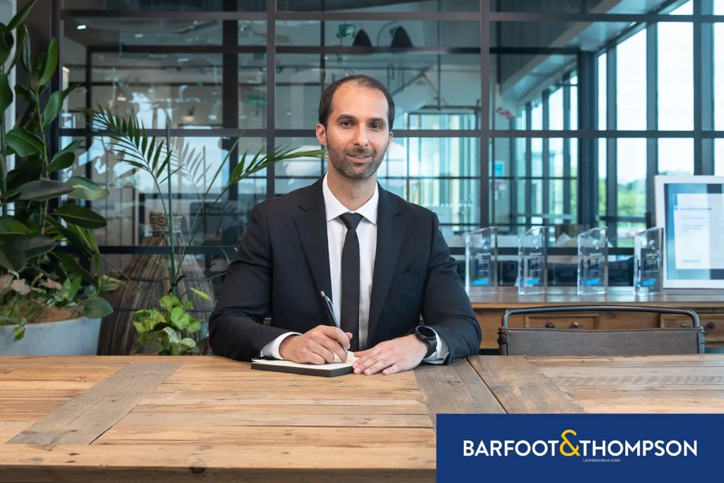 Professional Barfoot & Thompson real estate agent in modern office preparing reliable market reports for North Shore real estate trends.