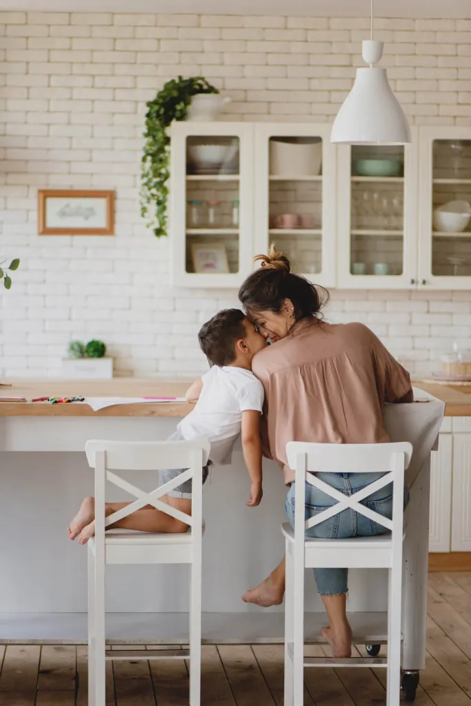 Mother and child sitting together in a bright modern kitchen while preparing their home for sale with Michael Hossaini.