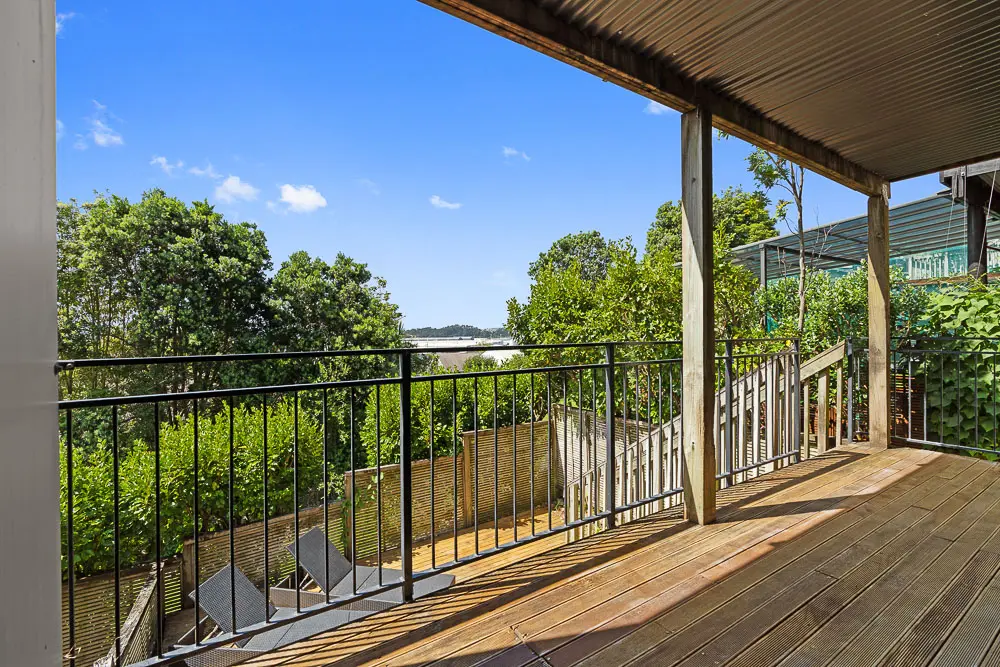 Covered lower-level balcony with stairs to private deck and leafy outlook.