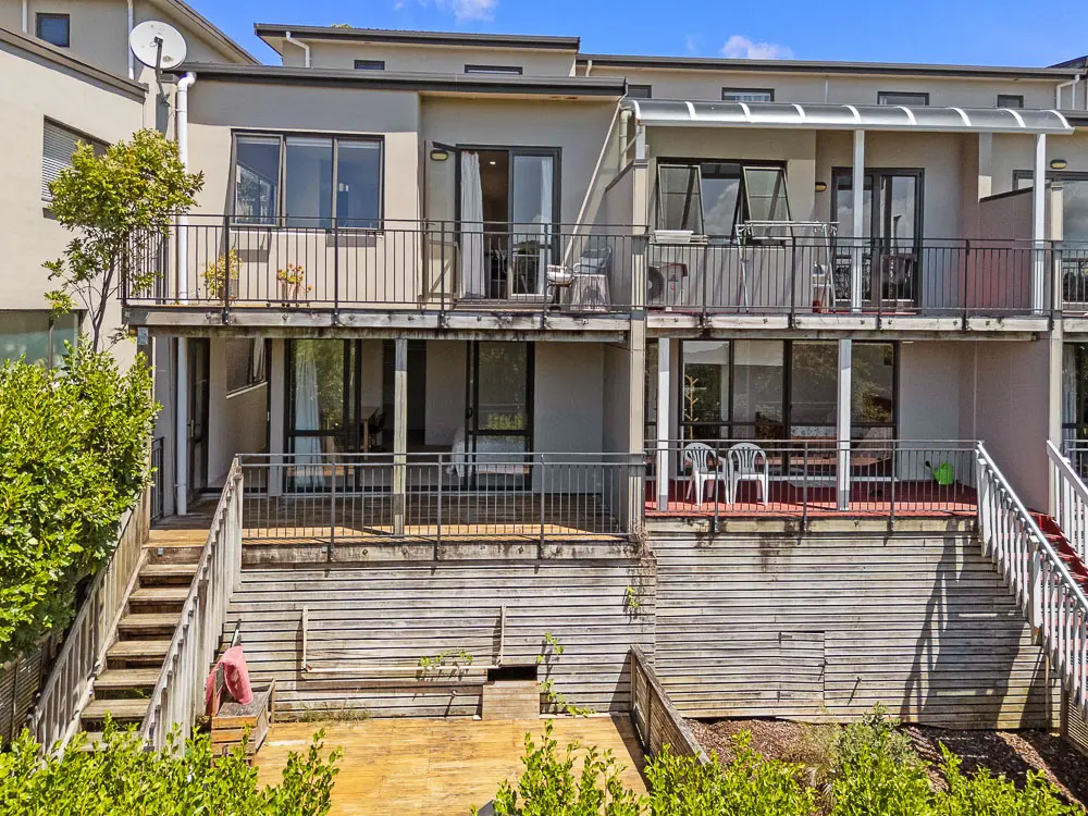 Rear exterior showing upper and lower balconies surrounded by greenery.
